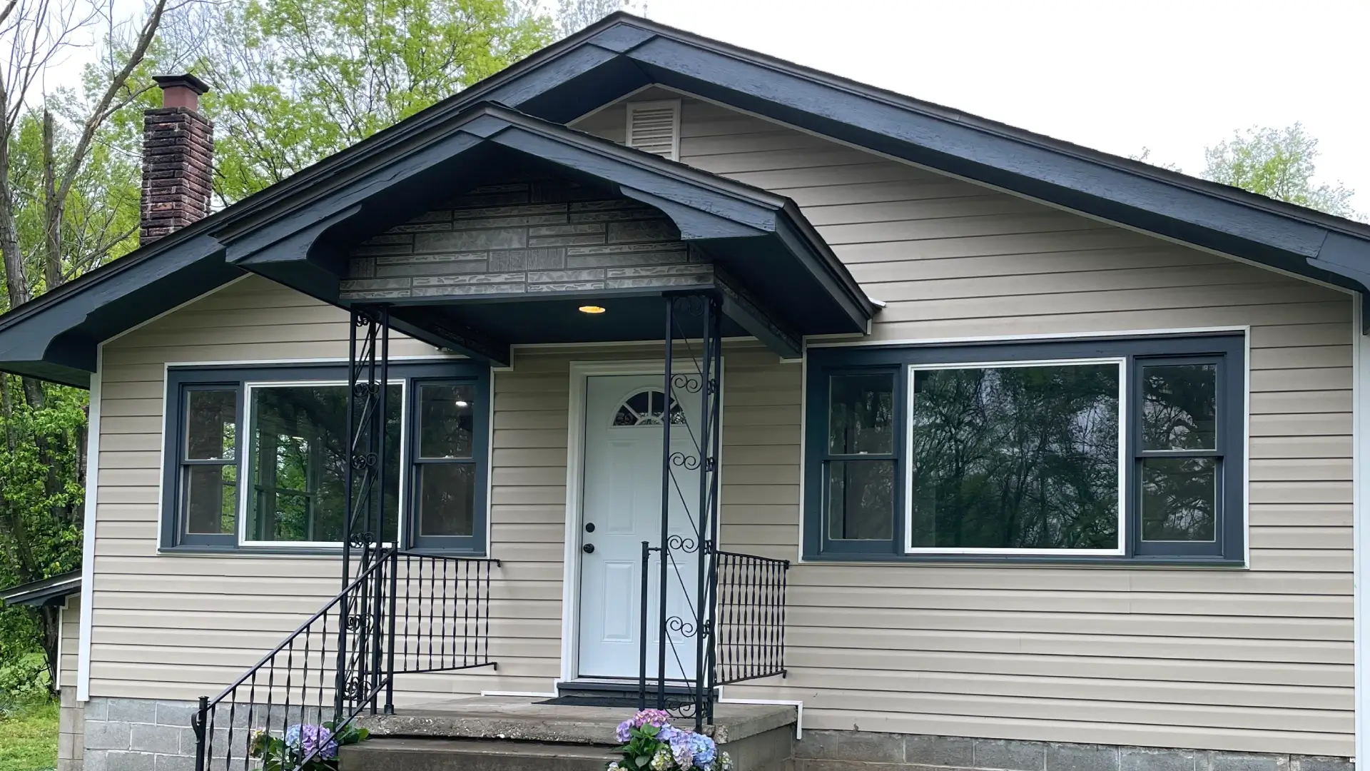 Front view of a single-story grey ranch house with a white front door.