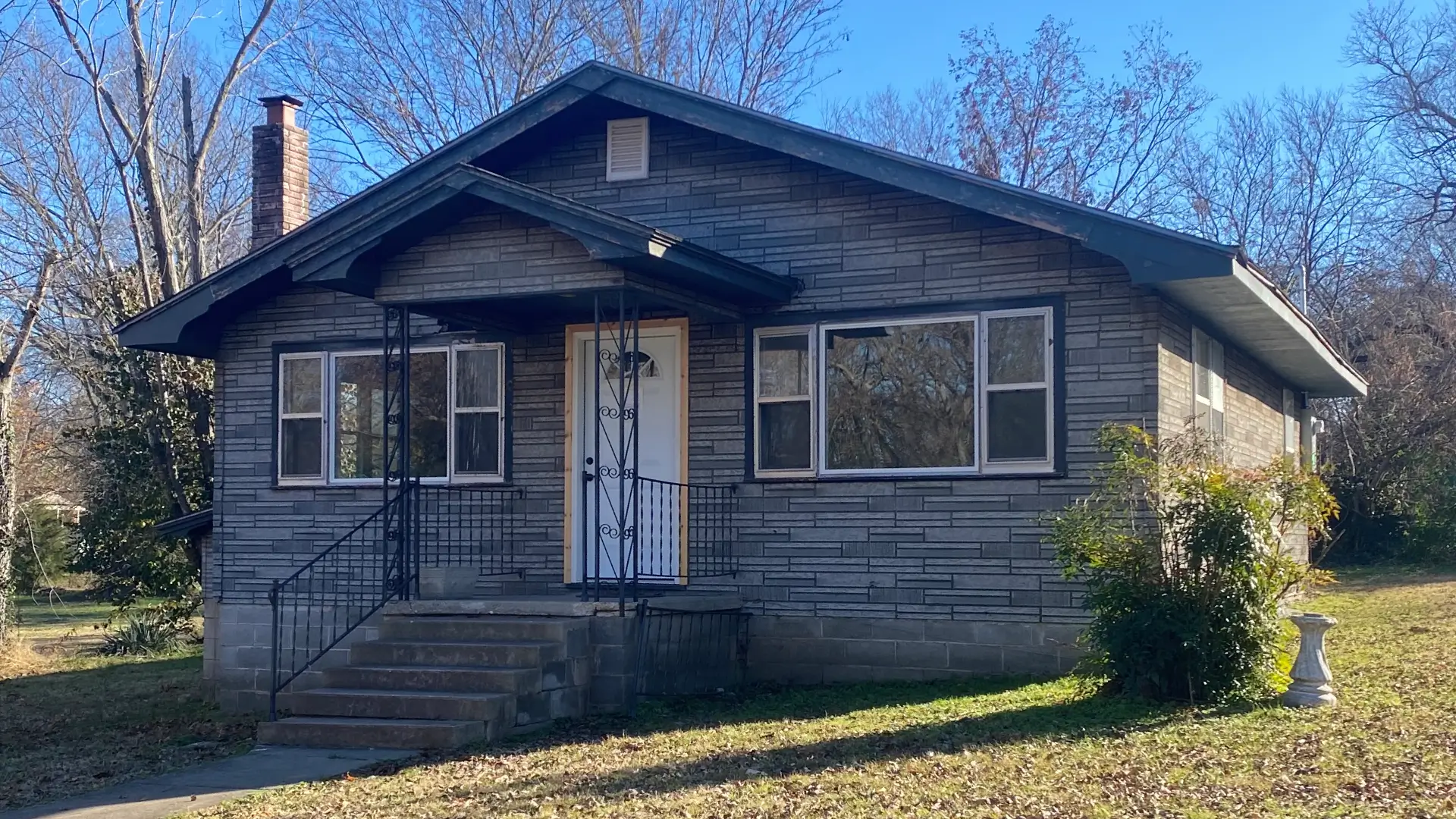 Frontal view of a grey suburban house featuring a small covered porch and steps.